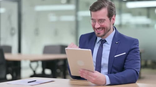 Excited Businessman Celebrating Success Using Tablet Device