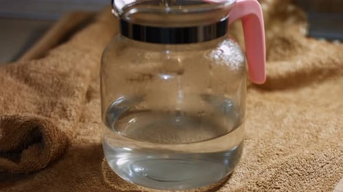 Pouring Tea Leaves into Water in Glass Pitcher