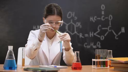 Chemiestudent tropft Flüssigkeit in Reagenzglas und schreibt Ergebnisse, Experiment