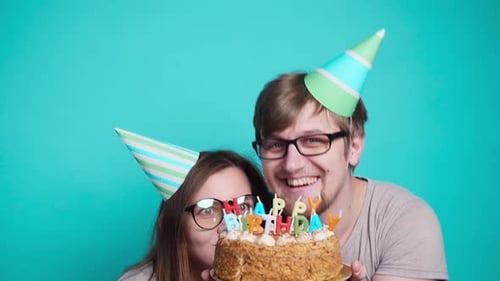 Couple Celebrating Birthday Holding Lit Cake and Smiling