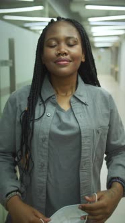 Young Woman Takes Off Mask in Hospital Hallway