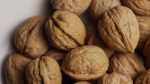 Cinématographique et rotatif de noix dans leur coquille sur une surface blanche - WALNUTS