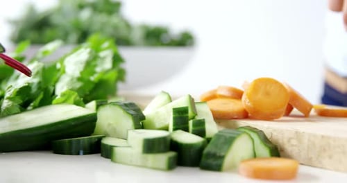 Mid-section of woman cutting vegetables on chopping board