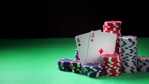 Stacks of Poker Chips and Two Aces on Green Table and Black Background in Close-up