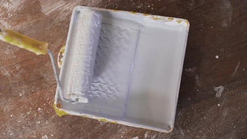Paint Roller Being Rolled in a Paint Tray