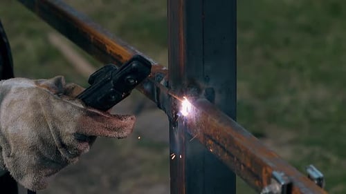 Close View Welder construye una cerca con tablas utilizando una herramienta moderna