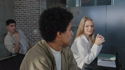 Jeunes élèves du groupe diversifié assis en classe à la leçon répondant à une question discutant d'un nouveau sujet