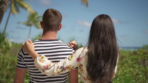 A man and woman couple walking on a path in the tropical islands in French Polynesia.