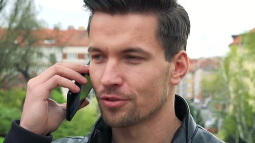 Young Handsome Man Stands and Talks To Somebody on Phone in Park - Detail of Face