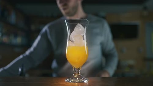 Bartender Making Cocktail Adding Ice and Yellow Liquid