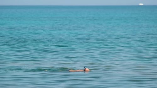 Unrecognizable Man Swimming with Snorkeling Breathing Mask Under Sea Water Surface