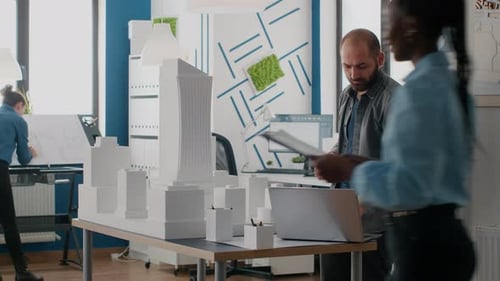 Architekt arbeitet mit Laptop und Gebäudemodell, um einen Bauplan zu entwerfen