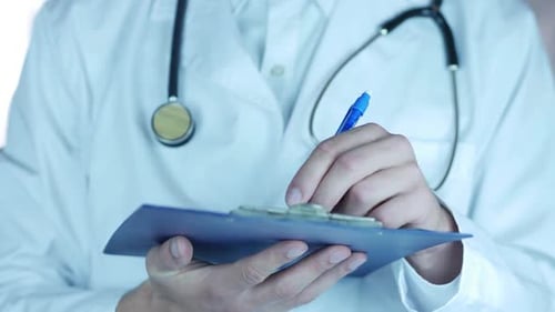 Doctor Writes on Clipboard in Medical Setting