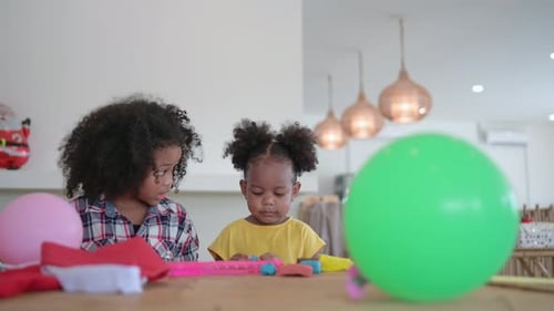 Two little girls Playing with plasticine in various shapes merrily