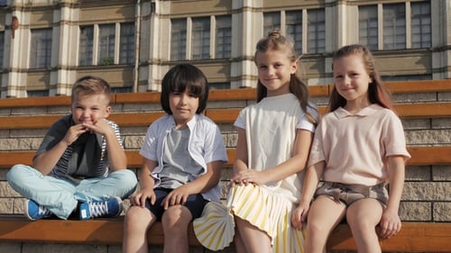 Smiling Children Sitting on a Bench Together