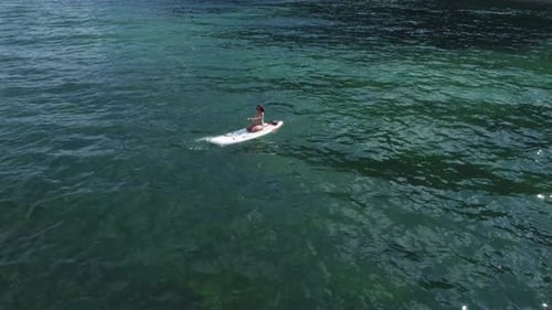 Aerial Drone View of Young Woman Sitting on a Paddle Board or Sup in the Sea
