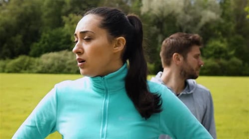 Woman Sweating After Workout with Man in Background