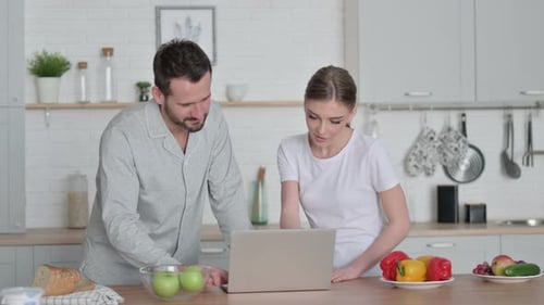 Young Couple Using Laptop in Bright Kitchen