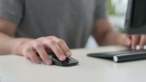 Hands of Young Man Using Mouse on Desktop Close Up