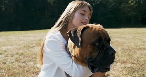 Woman Hugging Dog in a Grassy Field