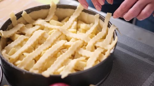 Hands Decorating Apple Pie with Lattice Crust