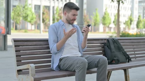 Young Adult Frustrated Using Smartphone on Bench