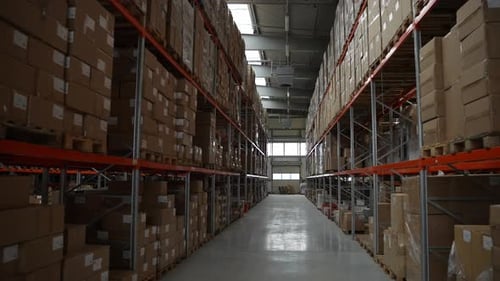 Une allée entre des étagères pleines de boîtes dans un entrepôt