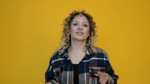 Smiling Woman Dances in Front of Yellow Background