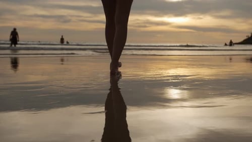 Woman Walking Into the Sea Over Sunset