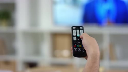 Hand des Mannes mit TV-Fernbedienung zu Hause