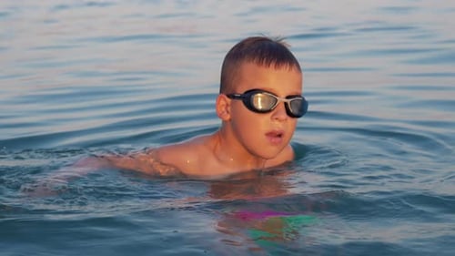 Kid with ball bathing in the sea