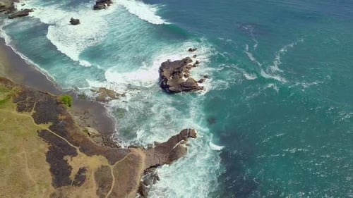 Aerial Top Down View of Ocean Waves Breaking on the Rocky Coast Line in Summer.