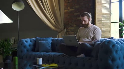 Man Using Laptop on Comfortable Sofa at Home