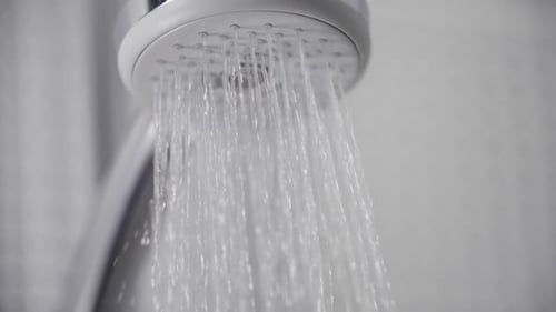 Close-Up Turning on Shower Head in Bathroom, White Tiles on Walls Water Flowing Falling Drops
