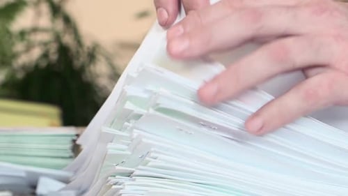 Man Leafing Through a Large Stack of Documents in the Office. Hands Close Up.