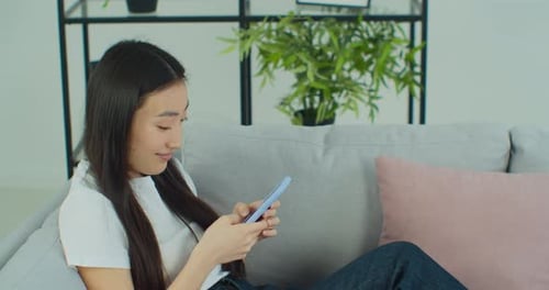 Woman Relaxing on Couch Using Mobile Phone