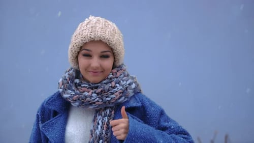 Portrait of a Smiling Woman Showing Thumbs Up Over Winter Background. Winter Concept. Snow and Woman