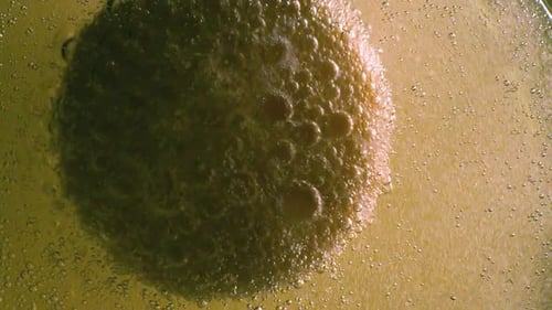 Bubbles Covering Golden Sphere in Liquid, Close Up