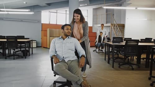 Office Workers Racing on Rolling Chairs in Workspace