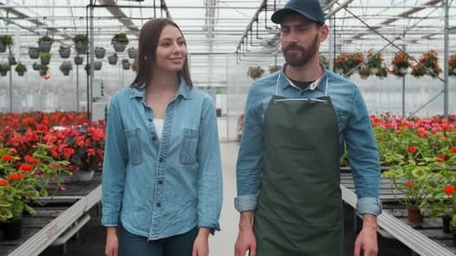 Confident Florists Smiling in Greenhouse Surrounded by Flowers
