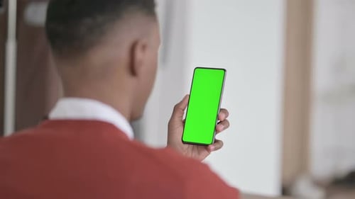 Rear View of African Man Holding Smartphone with Green Chroma Screen