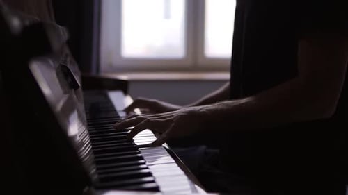 Hands Playing Piano Keys in Dark Room