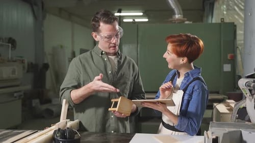 Two Carpenters Working with Equipment on Wooden Table in Carpentry Shop