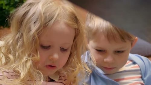 Girl and Boy Reading Book Together Indoors