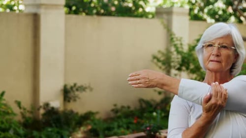 Senior woman with female trainer doing stretching exercise in garden 4k