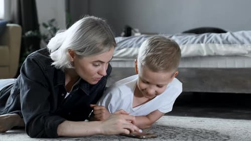 Woman and Child Using Cell Phone on Floor