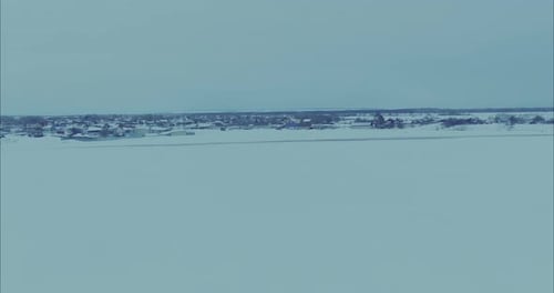 Copter Flies Up to a Large Village a Snowwhite Field and a Country Road