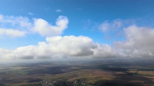 Aerial View From Airplane Window at High Altitude of Earth Covered with White Puffy Cumulus Clouds