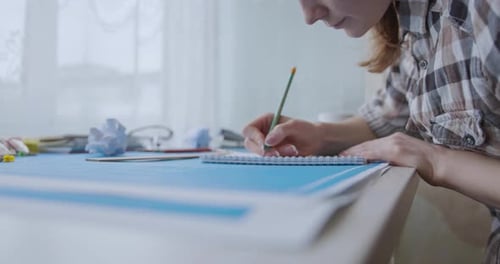 Woman Writes in Notebook at Her Desk