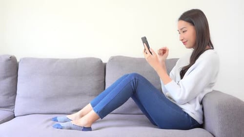 Woman Relaxing on Couch Using Mobile Phone